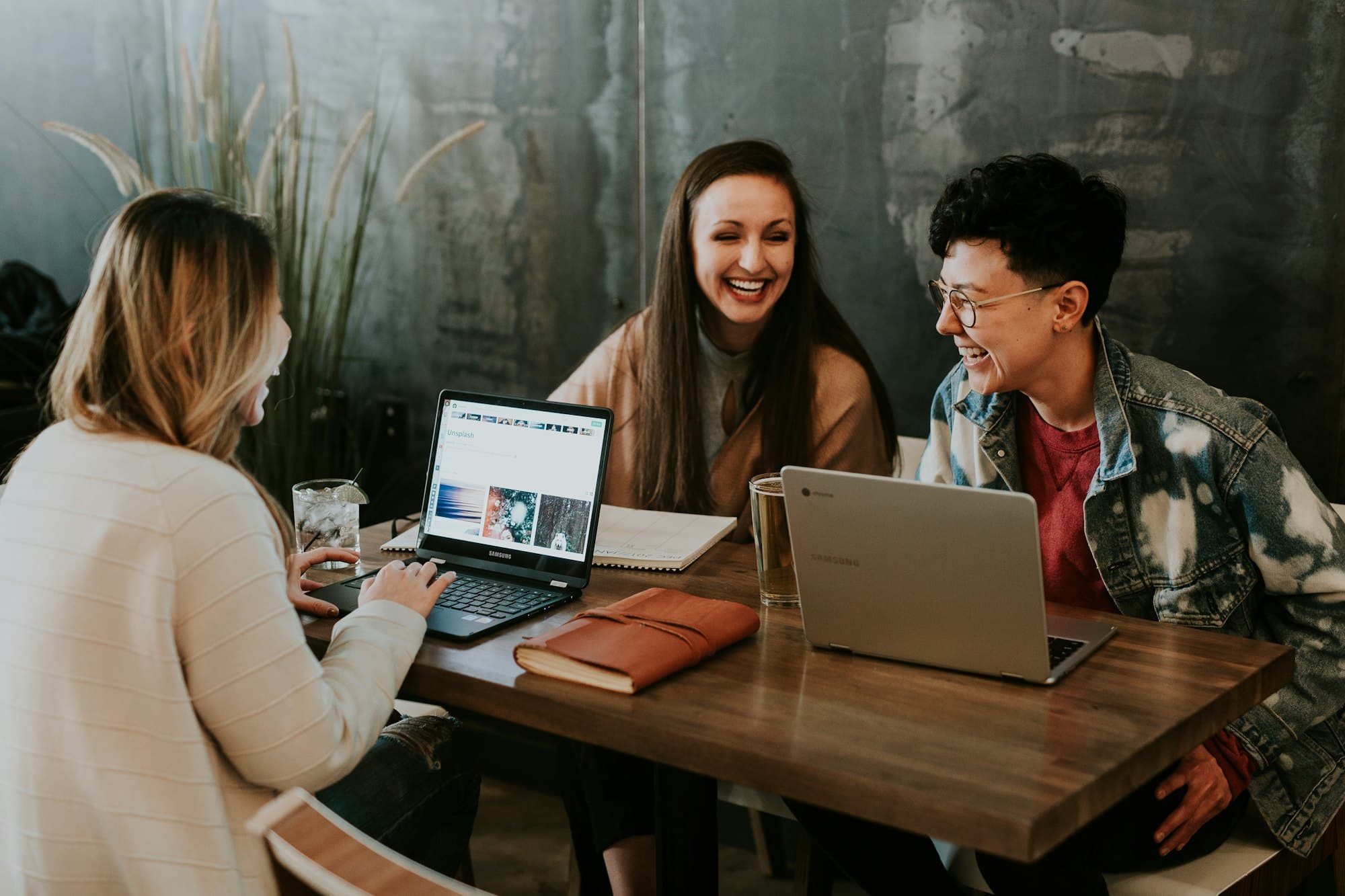 Three people working on laptops around a café table